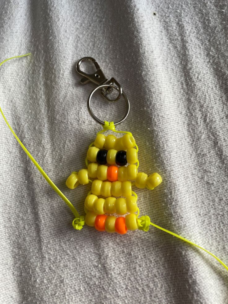 a keychain made out of corn on the cob with black eyes and an orange nose