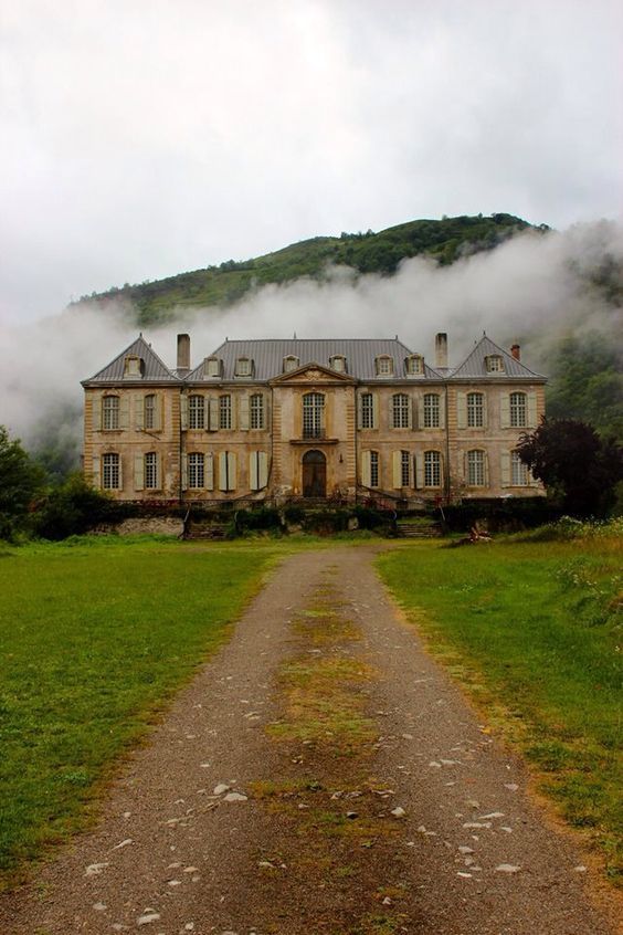 an old house in the middle of a field with fog coming from it's windows