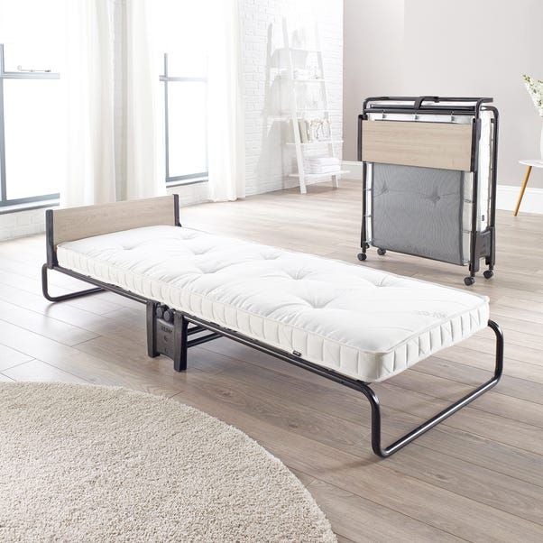 a white bed sitting on top of a wooden floor next to a baby crib