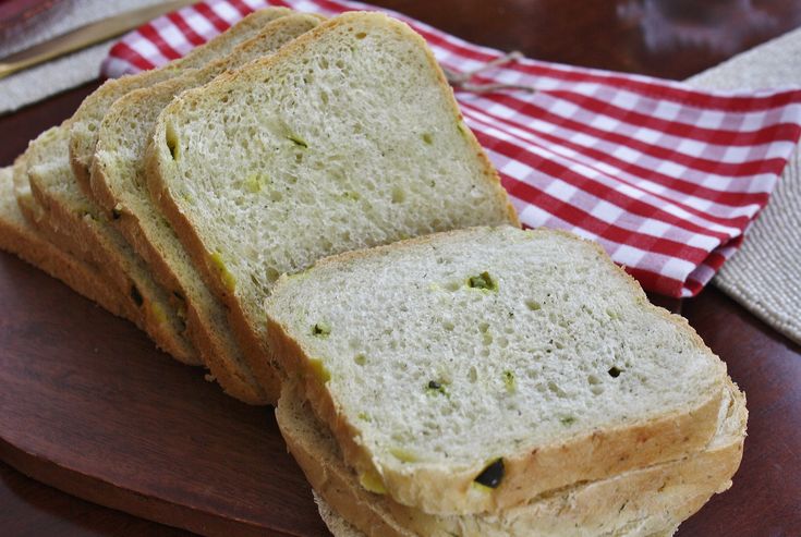 four slices of white bread on a wooden plate with a red and white checkered napkin