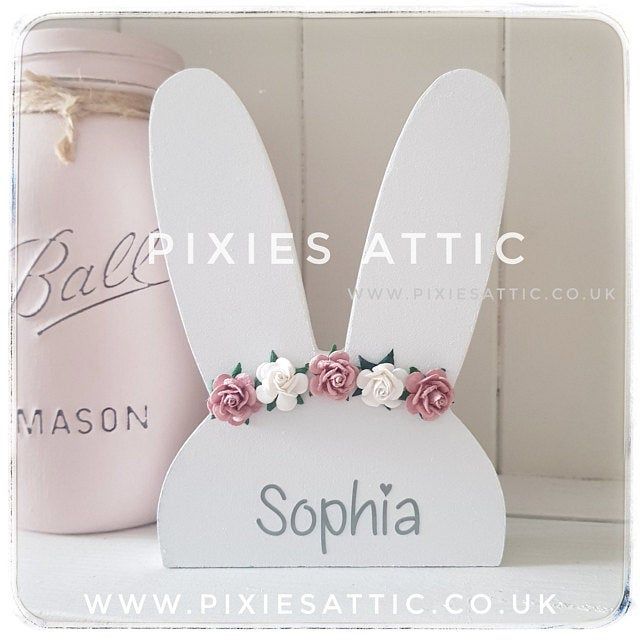 a white rabbit shaped box with pink flowers on it's ears and name written in english