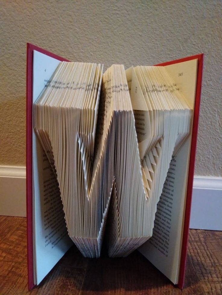 an open book sitting on top of a wooden floor next to a white wall with red trim