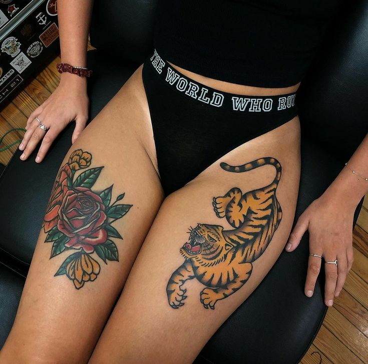 a woman with tattoos on her legs sitting in a chair next to a cat and rose tattoo