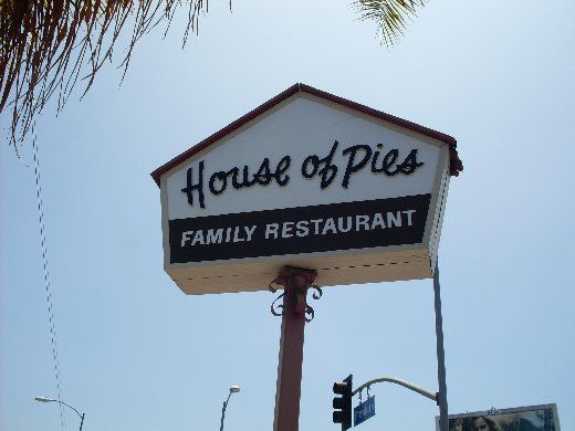 a sign for the house of pies family restaurant in front of a palm tree