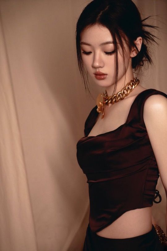 a woman in a brown top and black skirt with a gold chain around her neck