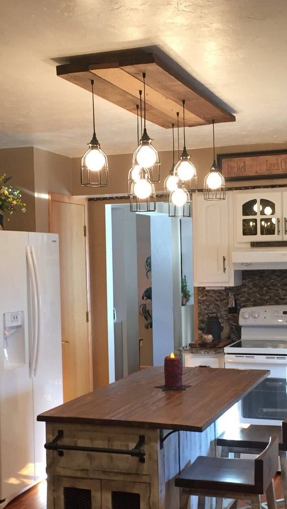 a kitchen island with stools in front of it and lights hanging from the ceiling