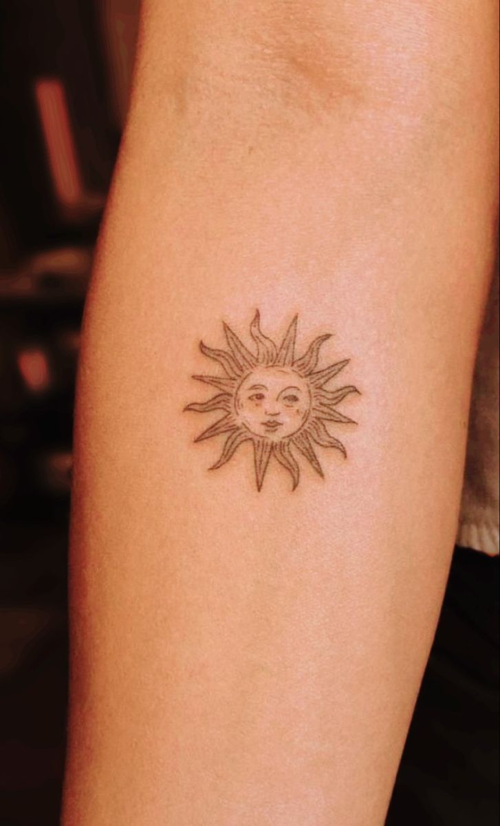 a small sun tattoo on the arm