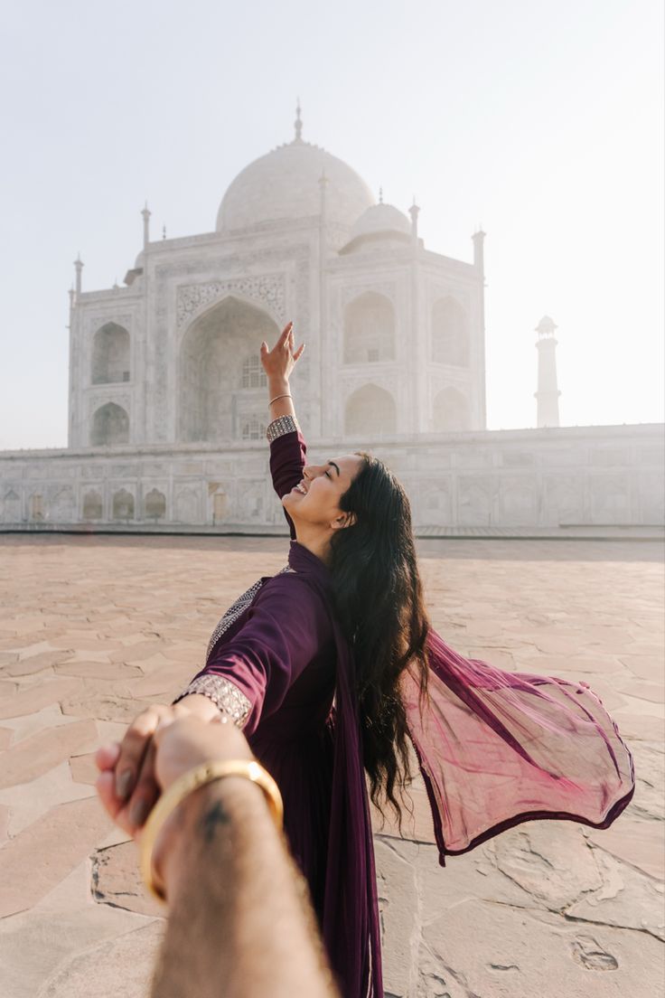 a woman is holding her hand up in front of the tajwak mosque