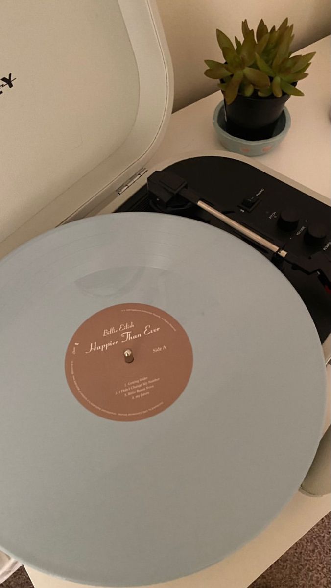 a record player sitting on top of a white table next to a potted plant