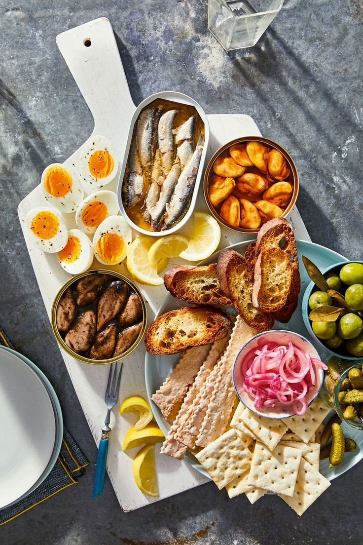 an assortment of food is displayed on a table with utensils and plates in front of it