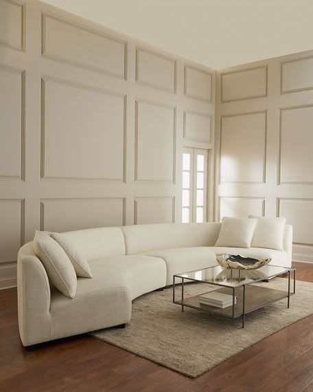 a white couch sitting on top of a wooden floor in a living room next to a window