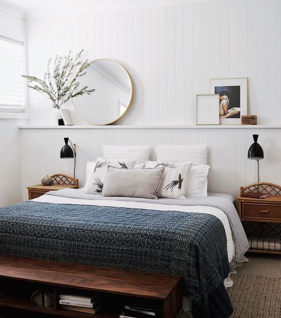 a bedroom with white walls and wood furniture, including a bed that has pillows on it