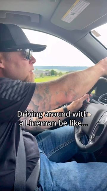 a man sitting in the driver's seat of a car with his hand on the steering wheel