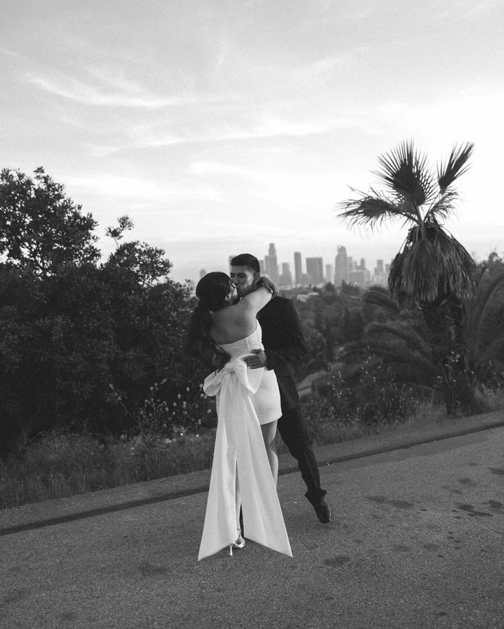 a man and woman embracing each other in front of a cityscape with palm trees