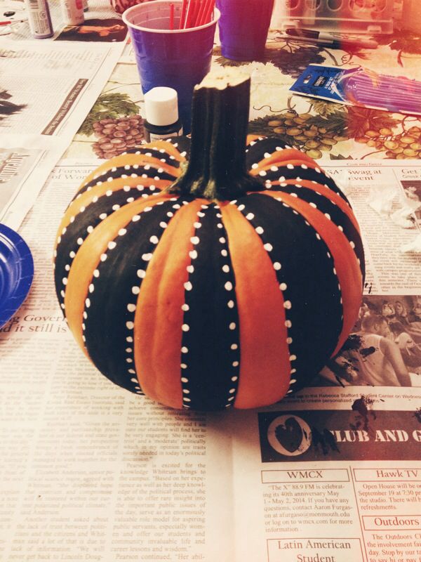 a black and orange pumpkin sitting on top of a newspaper