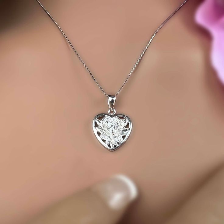 Double the love with two hearts on one pendant! A sparkling clear heart shaped cubic zirconia is framed with a cutout Hawaiian Scroll heart shaped design. Perfect for the special wahine in your life. This .925 sterling silver pendant includes a matching adjustable 18 inch chain. .925 Sterling Silver Cubic Zirconia Heart Shaped Stone Approximately 3/4" x 5/8" Includes 18" Adjustable Chain Sterling Silver Heart Pendant With Prong Setting, Sterling Silver Heart Pendant Jewelry With Prong Setting, Gift Heart Necklace With Prong Setting, Cubic Zirconia Heart Cut Diamond Necklace, Heart Cut Cubic Zirconia Birthstone Necklace, Silver Heart Necklace With Birthstone - Cubic Zirconia, Silver Double Heart Jewelry With Prong Setting, Silver Heart Necklace With Diamond Cut Cubic Zirconia, Sterling Silver Heart Cut Diamond White Necklace