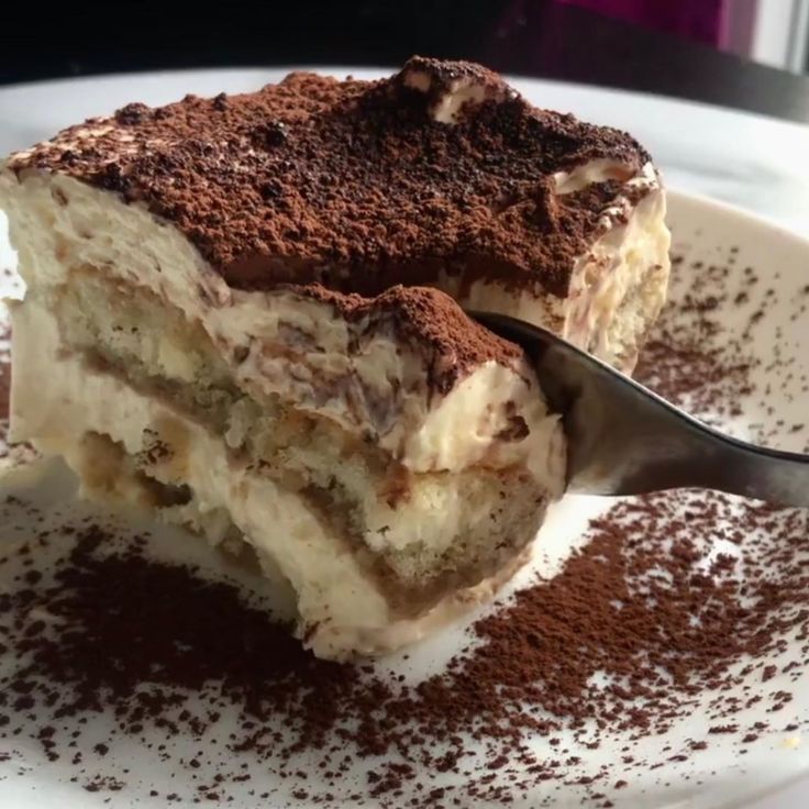 a piece of cake on a white plate with a spoon in it and chocolate sprinkles