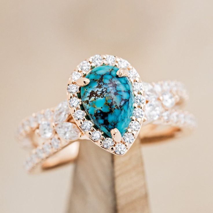 a ring with a blue stone surrounded by white and brown diamonds on top of a piece of wood