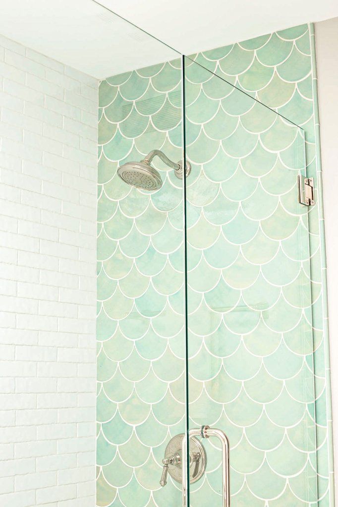 a bathroom with a glass shower door and tiled walls