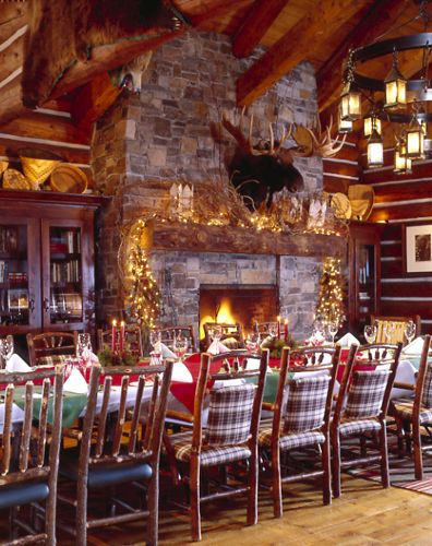 the dining room is decorated for christmas with deer heads hanging from the ceiling and fireplace