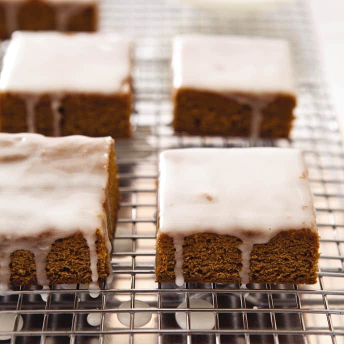 several pieces of cake sitting on top of a cooling rack covered in frosted icing