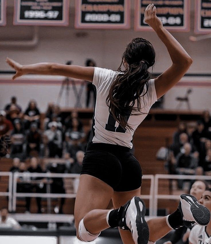 a woman jumping up in the air to hit a volleyball