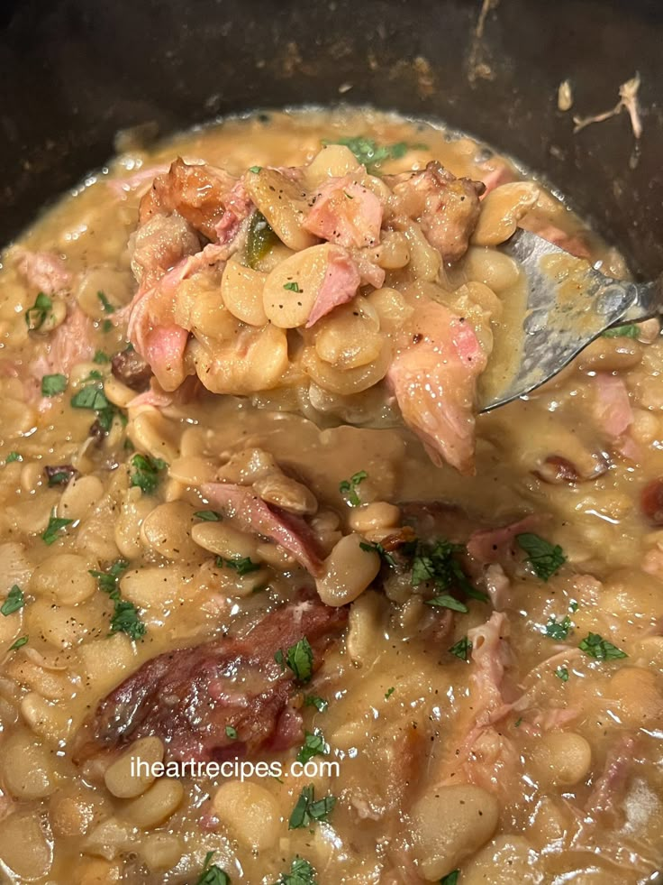 a spoon full of beans and ham in a pot