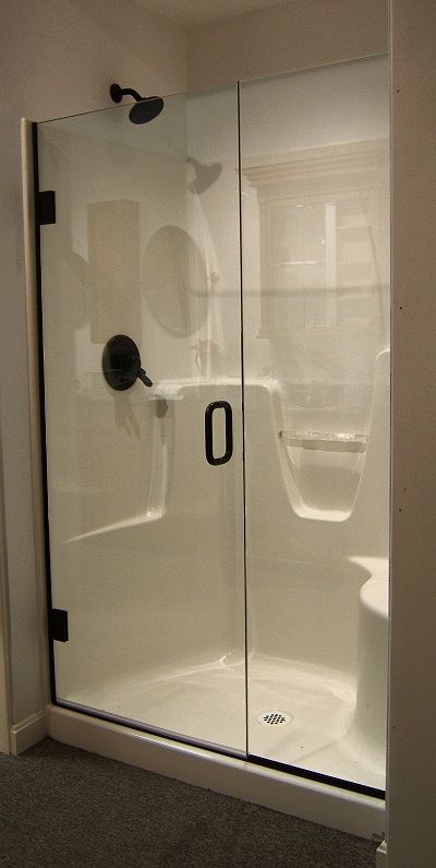 a bathroom with a glass shower door and black handles on the handlebars is shown