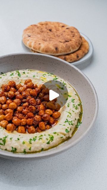 a bowl filled with hummus and garnish on top of a white table