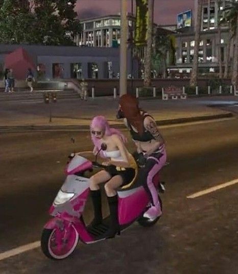 two people riding on the back of a pink scooter down a city street