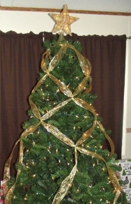 a christmas tree is decorated with gold ribbon