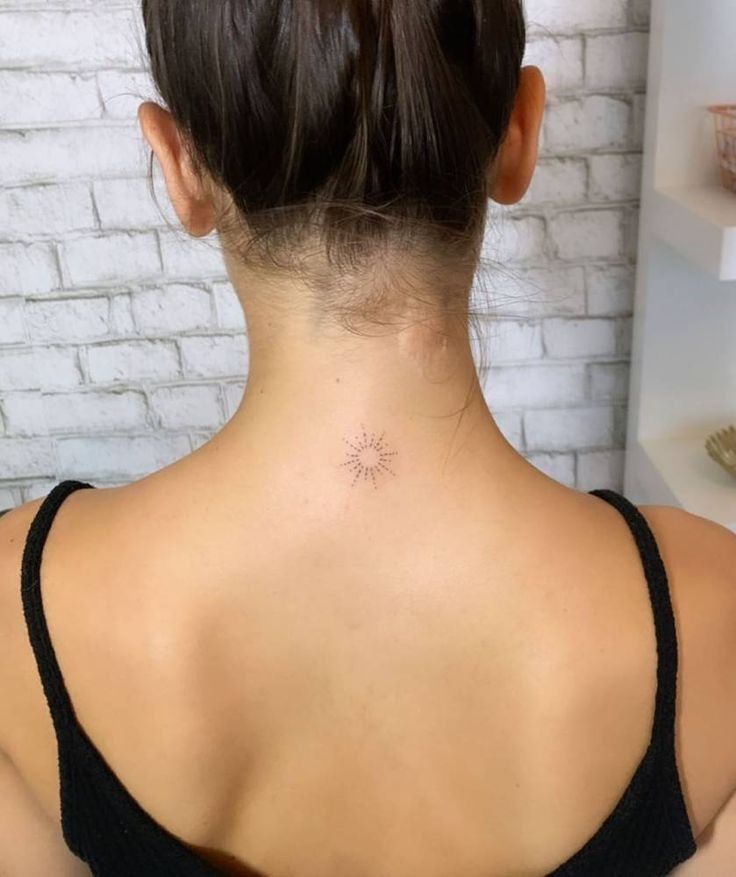 the back of a woman's neck with a small star tattoo on her left side