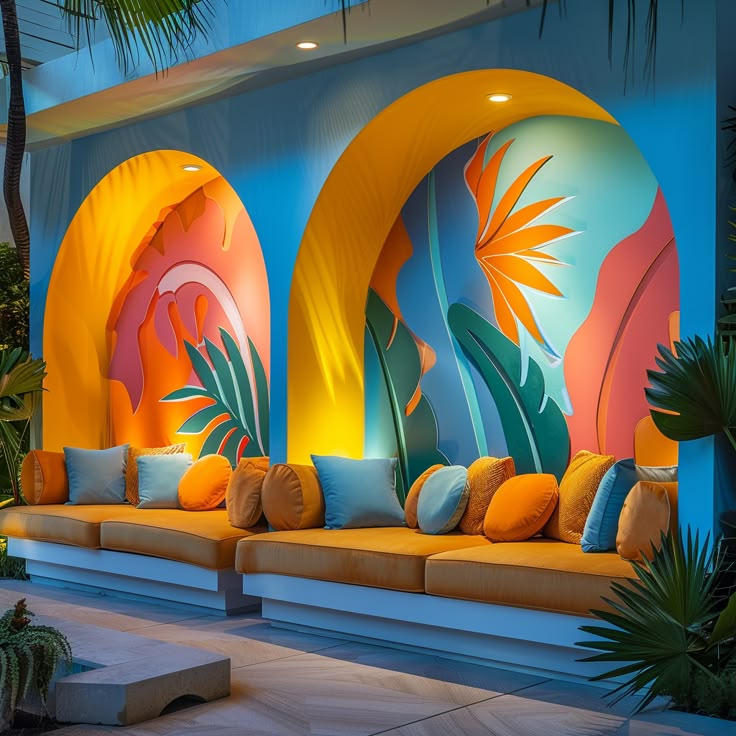 an outdoor seating area with colorful murals on the wall and palm trees in the background