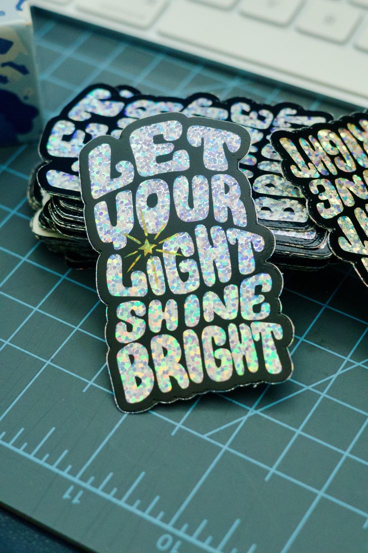 three stickers that say get your light shine bright on a table next to a keyboard