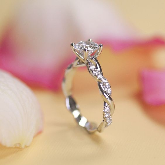 a diamond ring sitting on top of a table next to a sea shell and flower