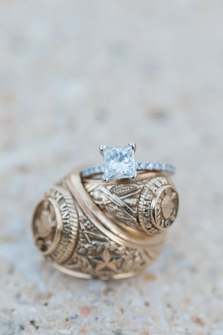 a gold ring with a princess cut diamond on top, sitting on a stone surface