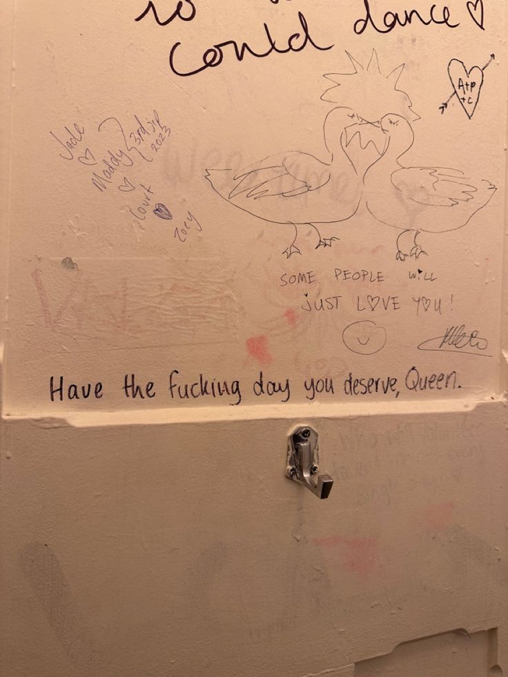 a bathroom stall with graffiti written on the wall