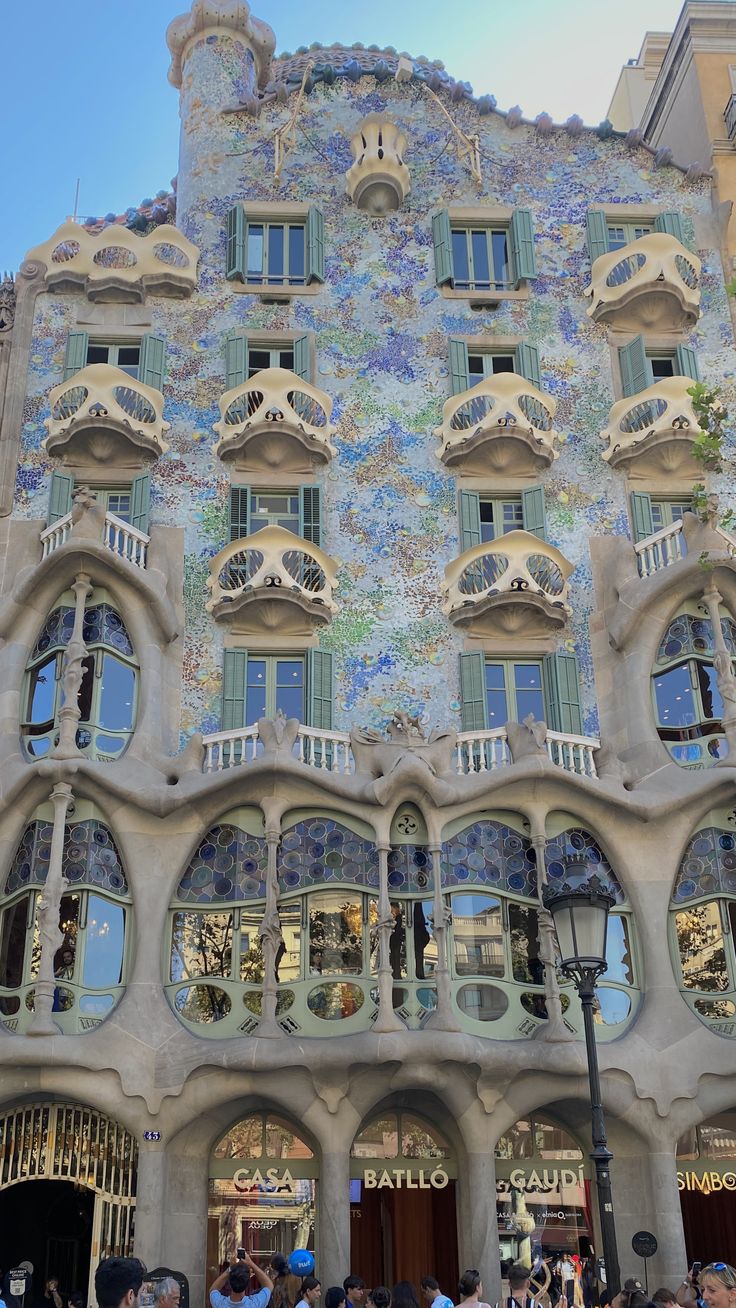 people are standing in front of a building with many windows and balconies on it