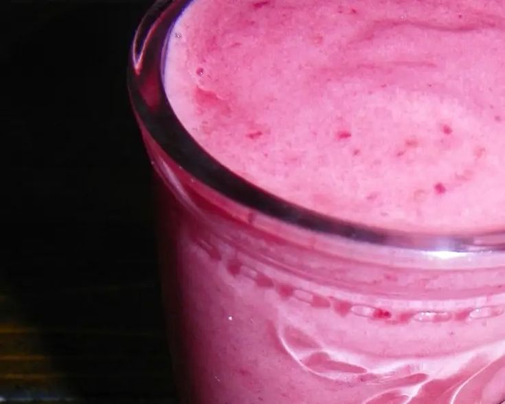 a pink smoothie in a clear glass on a table