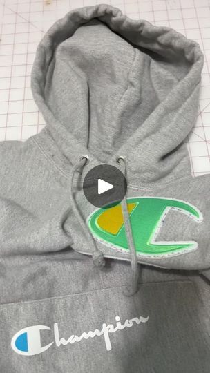 a gray champion hoodie with a green and yellow logo on the front, sitting on a cutting board