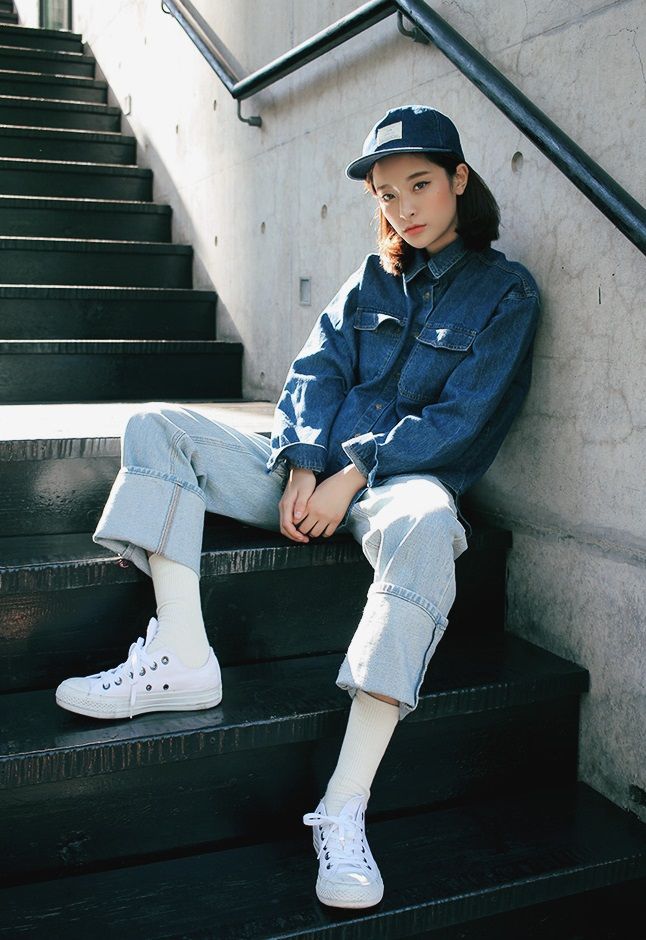 a young woman sitting on the steps with her legs crossed and wearing white tennis shoes