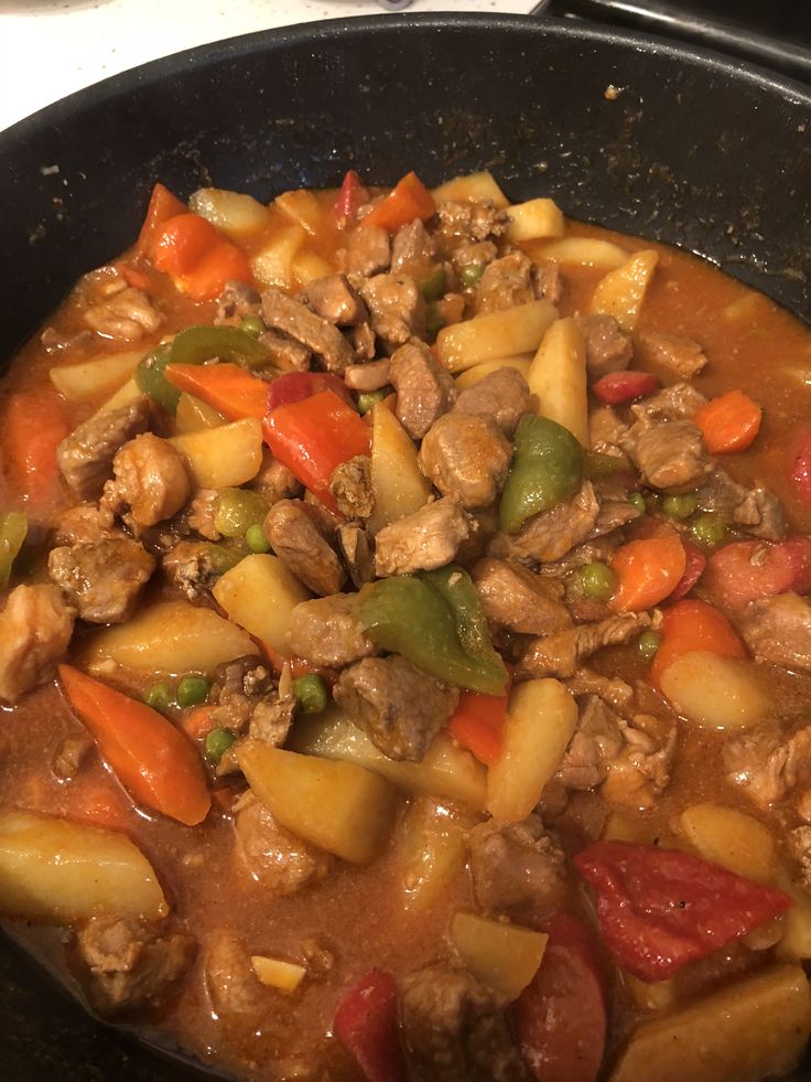 a skillet filled with meat and vegetables on top of a stove burner oven