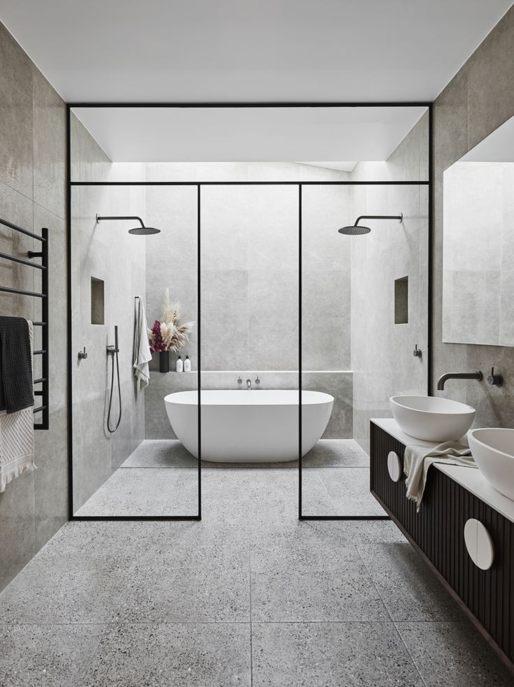 an image of a bathroom with glass walls and white tub in the center, shower stall to the right