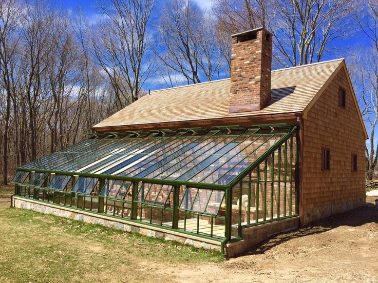 a small brick house with a green roof and glass doors on the front porch, surrounded by bare trees