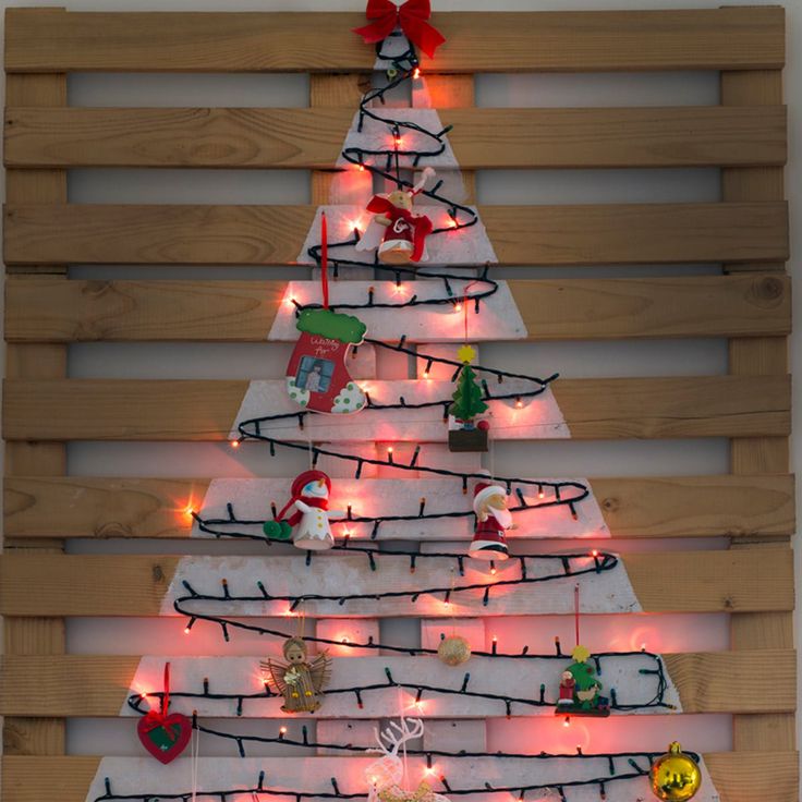 a christmas tree made out of pallet wood with lights on it and ornaments hanging from the top