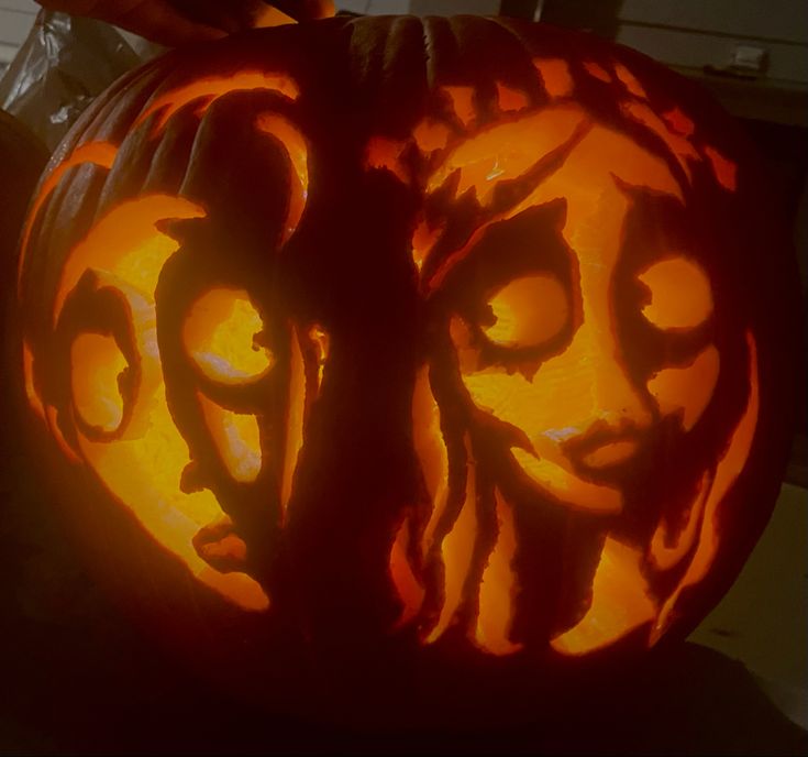 a carved pumpkin with faces on it in the shape of a woman's face