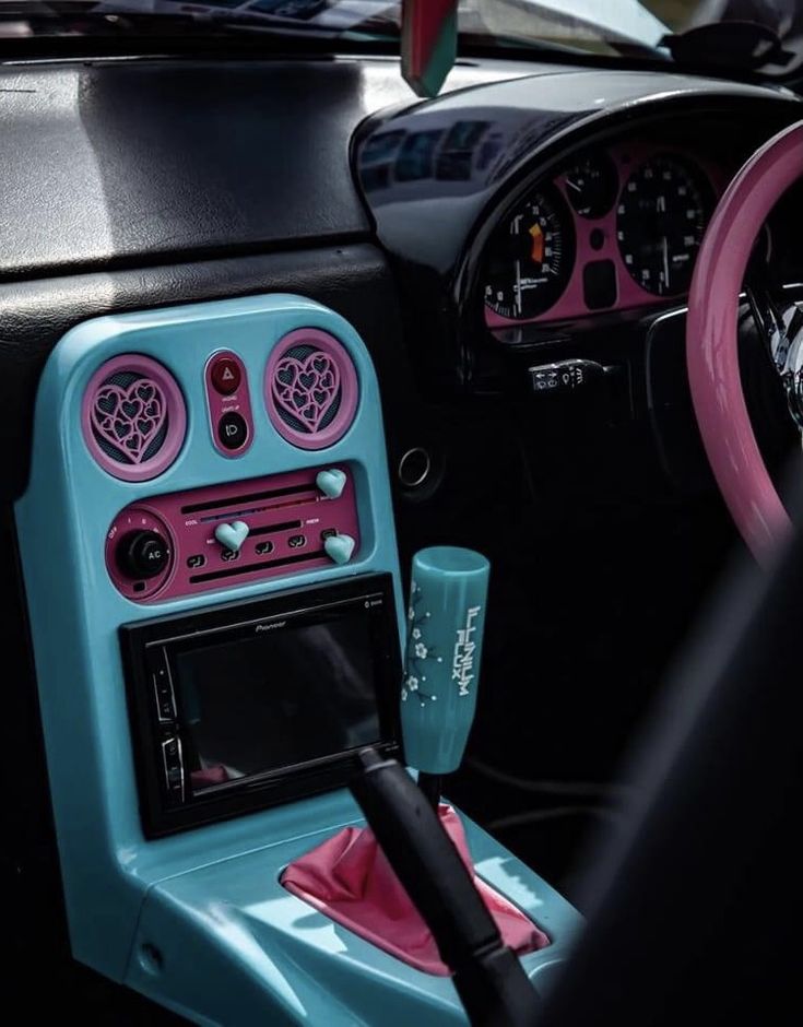 the interior of a car with pink and blue trims, steering wheel and dashboard