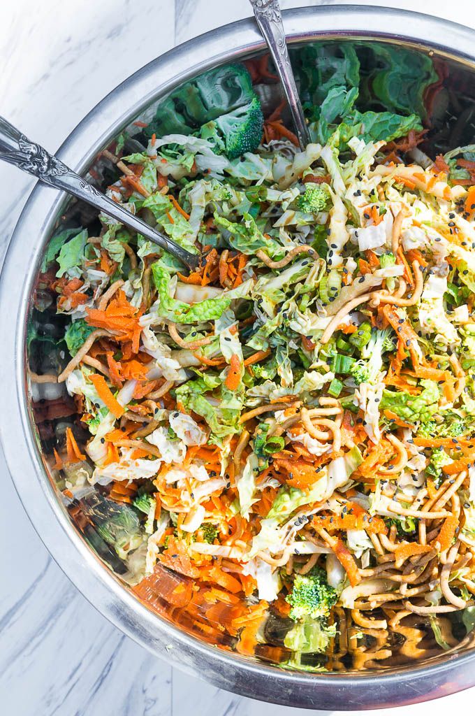 a bowl filled with shredded carrots, broccoli and other vegetables on top of a marble table