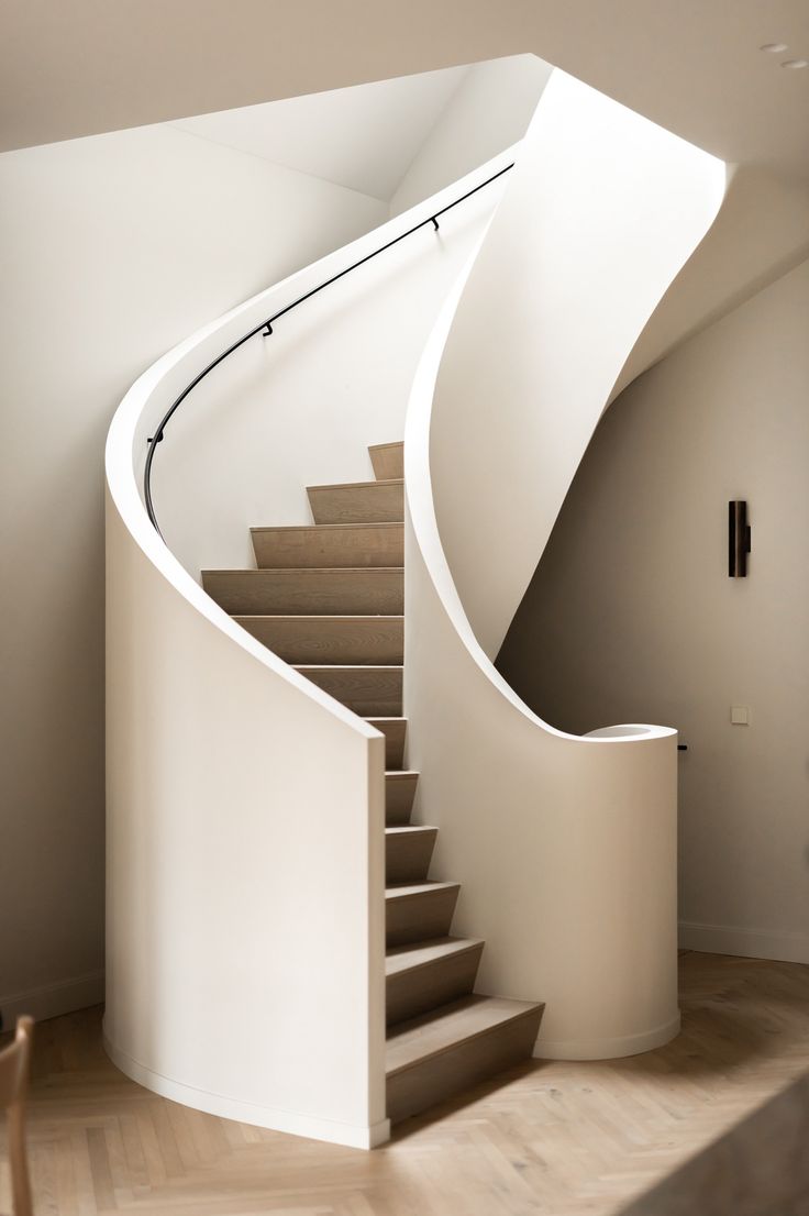 there is a spiral staircase in the house with white walls and wood flooring,