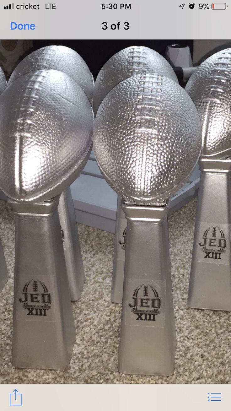 three shiny silver footballs sitting on top of a carpeted floor next to each other